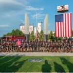 The riders pose under a big American flag.