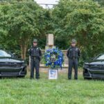 Two officers stand outside of a gravestone.