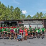 The riders take a picture in front of a fire truck.