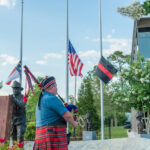 Bag pipes are played in front of American flags.