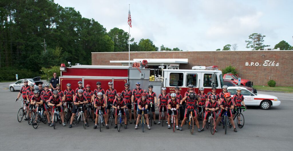 The riders in front of a firetruck.
